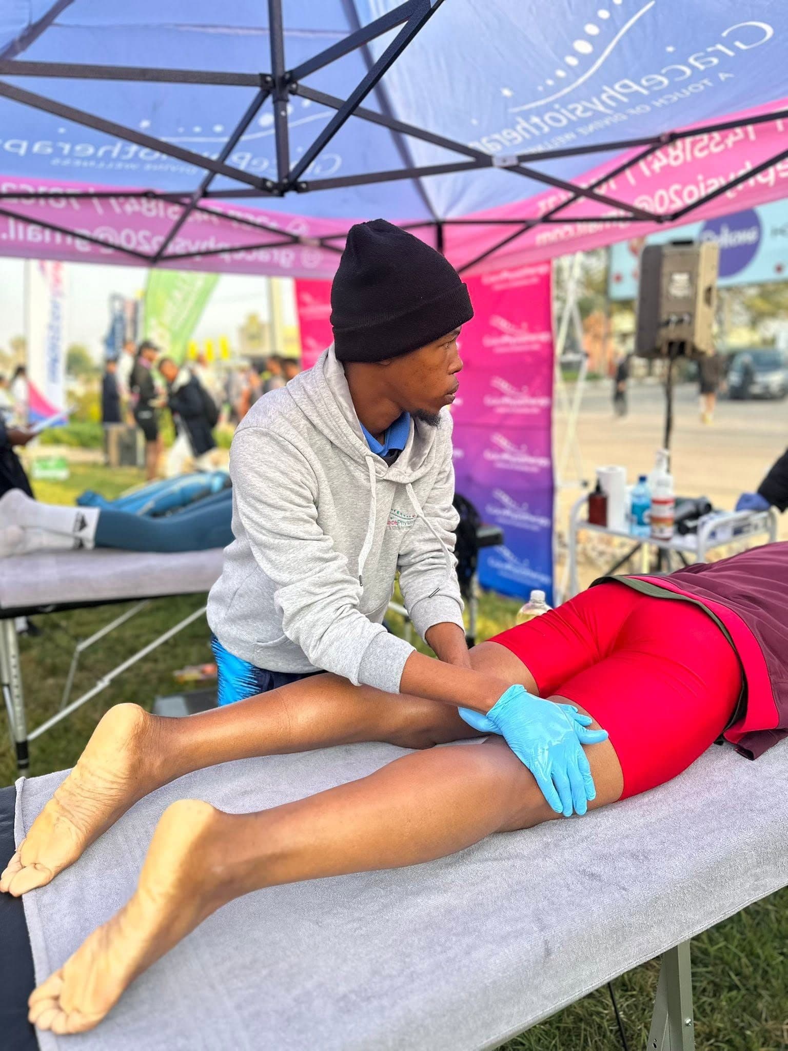 A Grace Physiotherapy therapist treating an athlete's leg on a treatment table at a Gaborone sporting event.