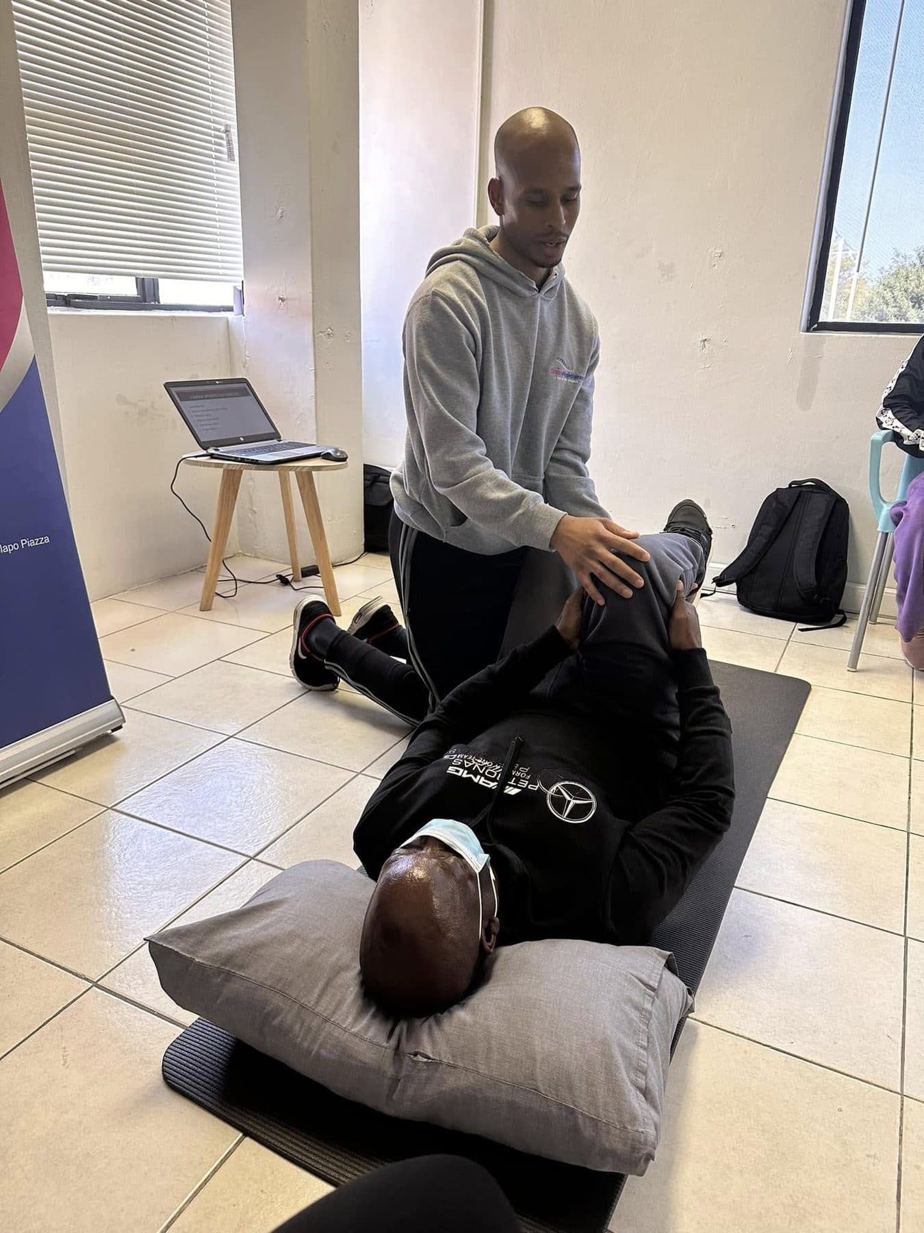 A Grace Physiotherapy therapist performing manual therapy on a patient lying on a treatment mat.