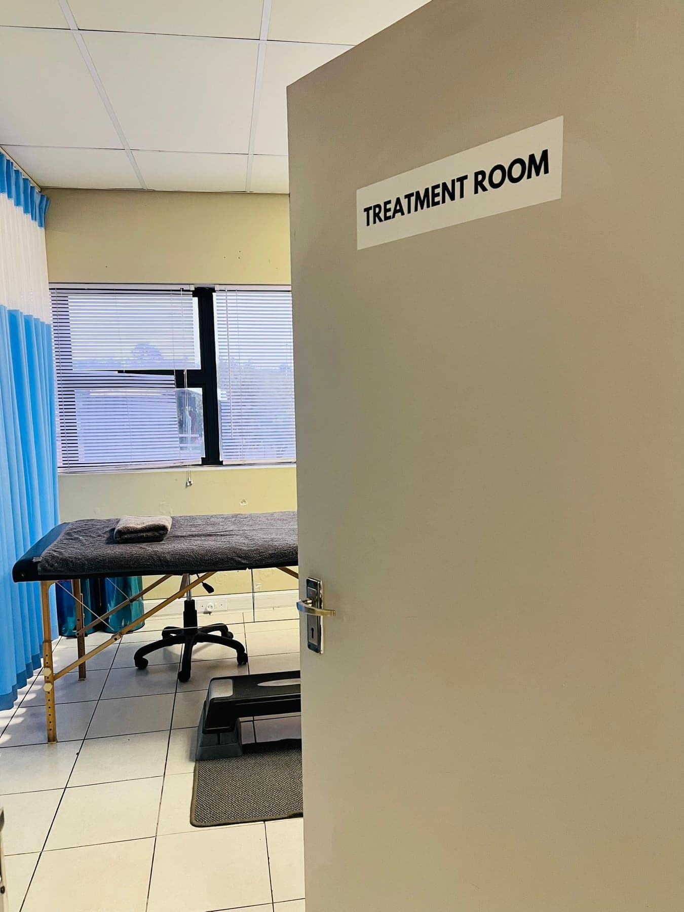 The signposted treatment room door at Molapo Crossing, open onto a treatment plinth and step platform.