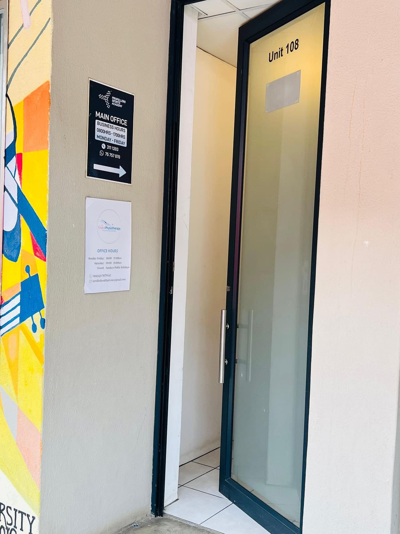 The Unit 108 glass entrance door to Grace Physiotherapy at Molapo Crossing, beside a painted mural and the Main Office signage.
